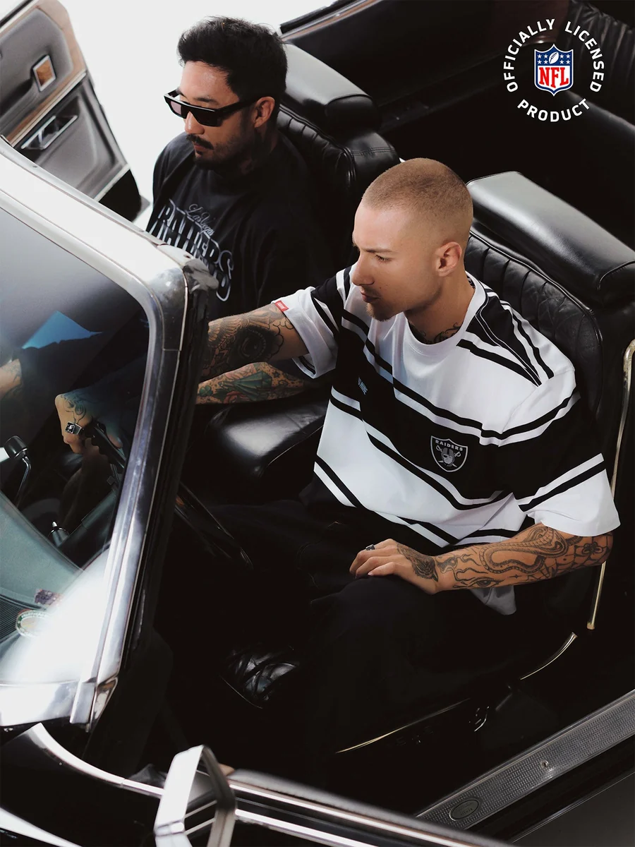 Dois modelos vestindo peças Raiders da Thug Nine dentro de um carro antigo