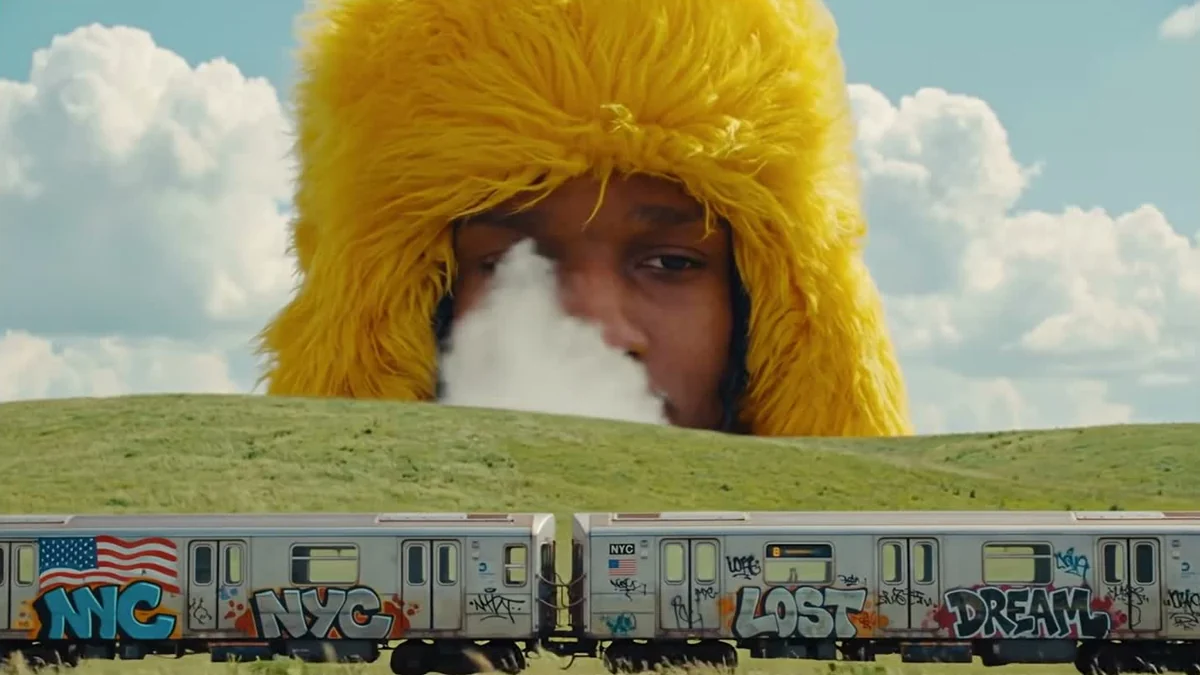 A$AP Rocky de capuz amarelo atrás de um vagão de metrô grafitado no clipe de Shroom Clouds