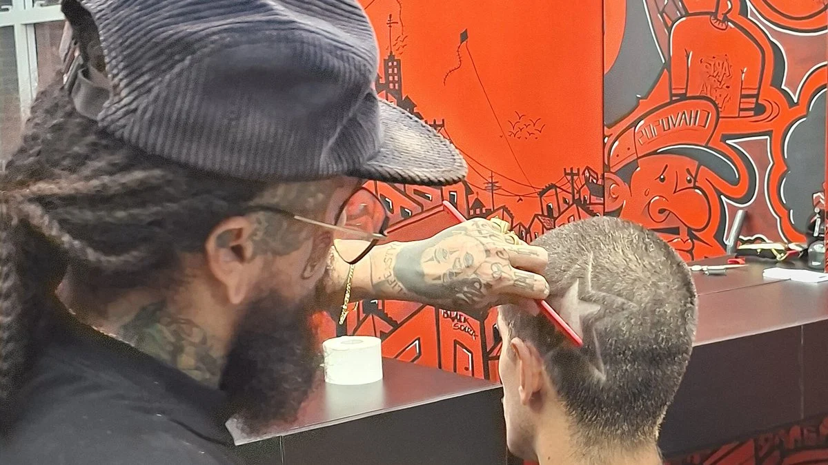 Barbeiro desenhando uma estrela na navalha no cabelo de um cliente, corte típico do estilo chavoso