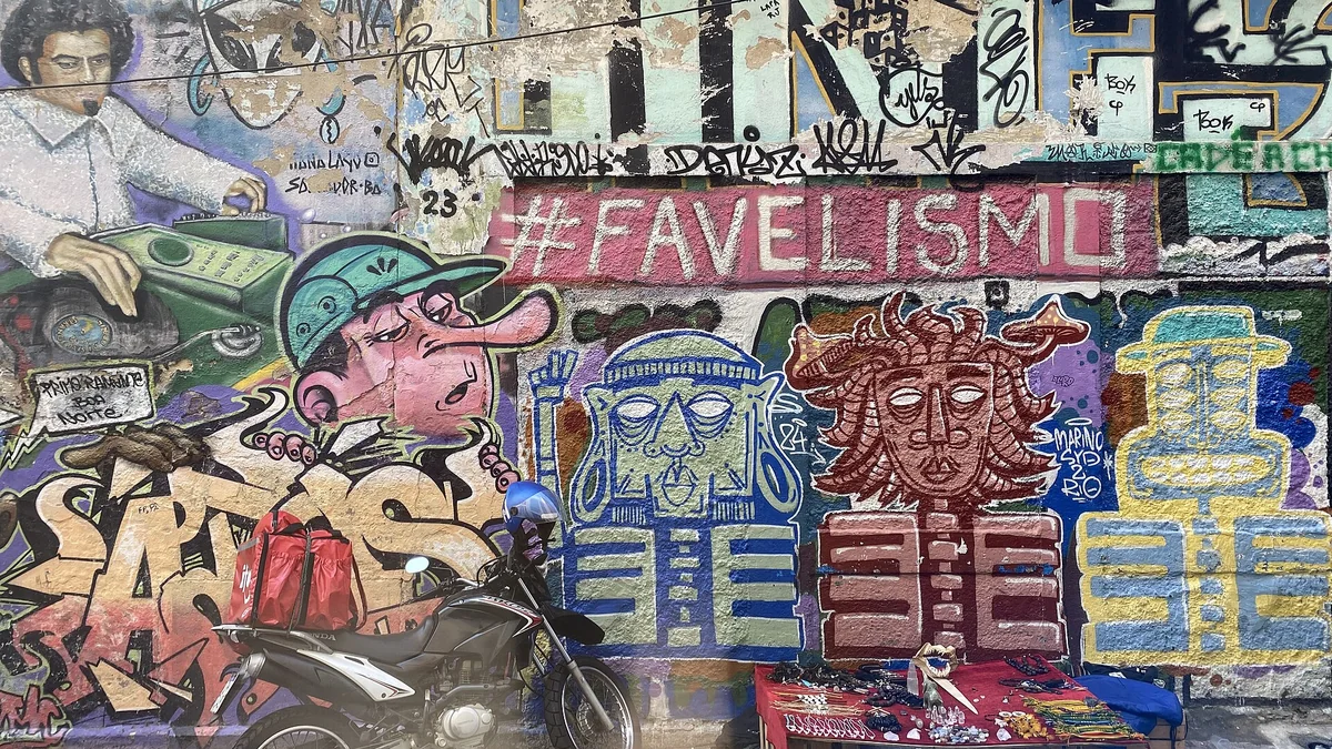 Muro grafitado com a palavra Favelismo e uma moto estacionada numa favela de Santa Teresa, no Rio de Janeiro