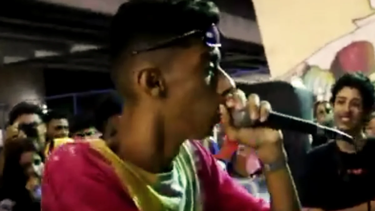 MC rimando ao microfone durante uma batalha de rima em Pernambuco, com o público ao fundo