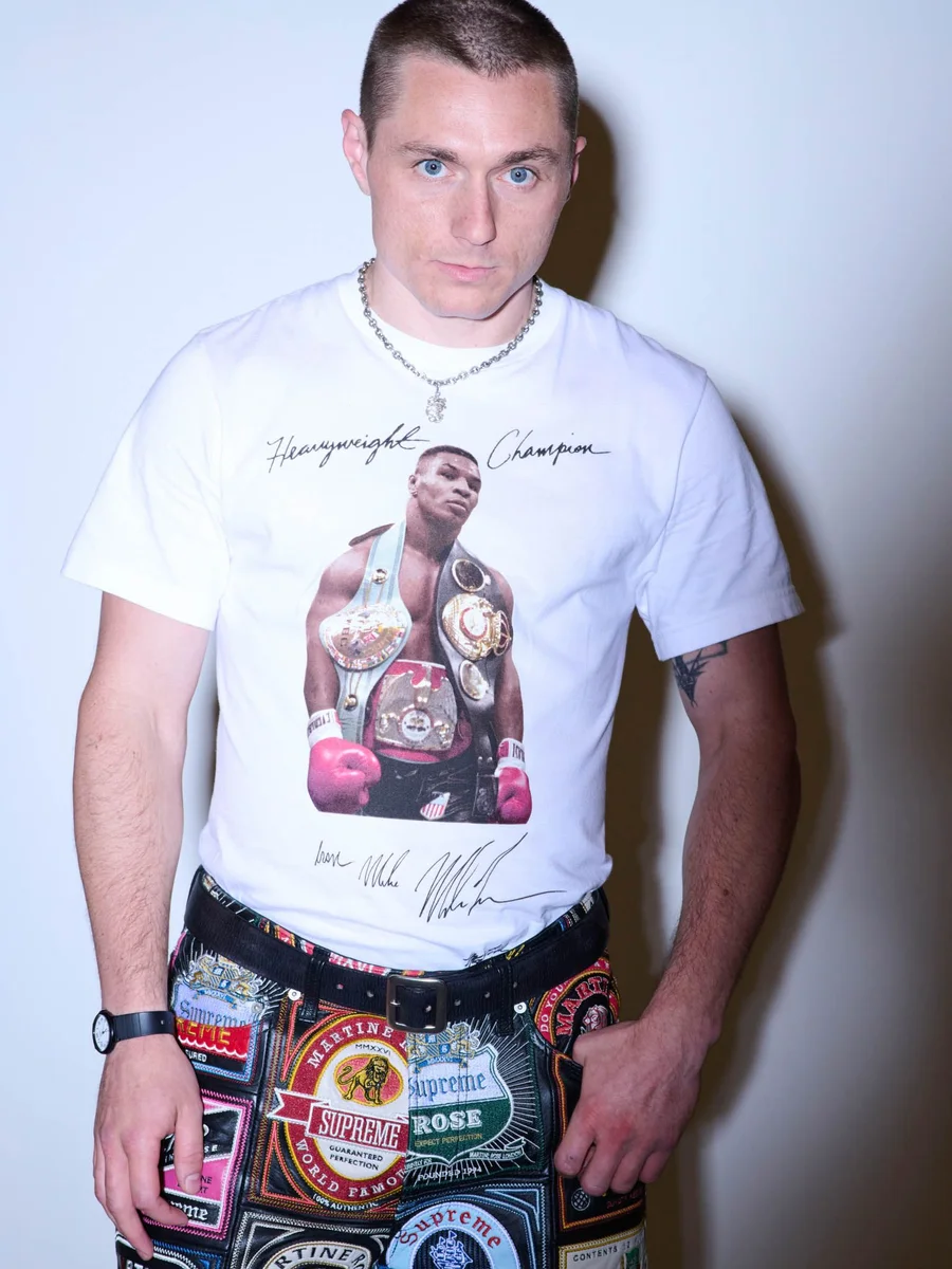 Modelo veste camiseta branca com foto de Mike Tyson segurando cinturões, da coleção Supreme e Martine Rose